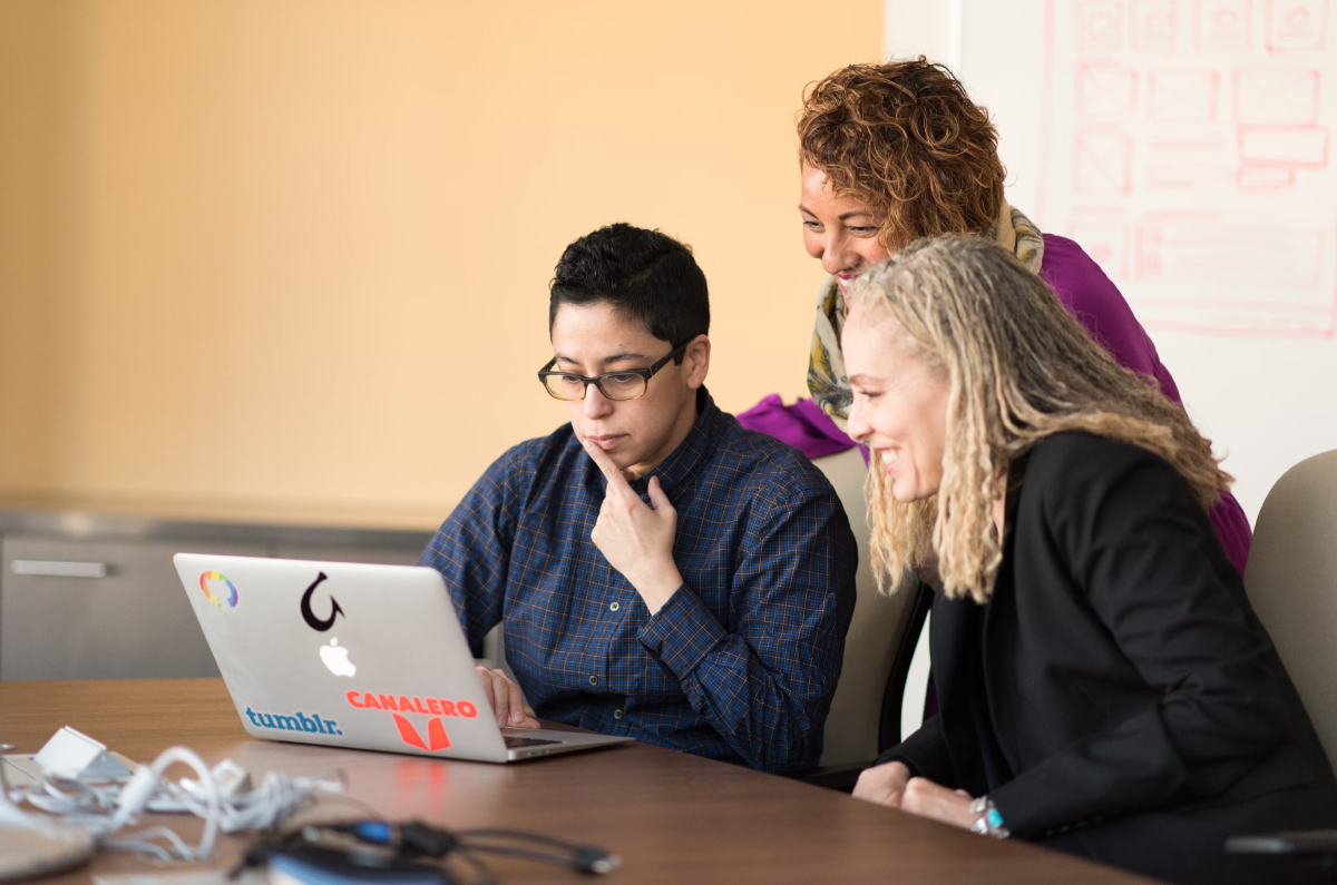 Three staff members around a laptop